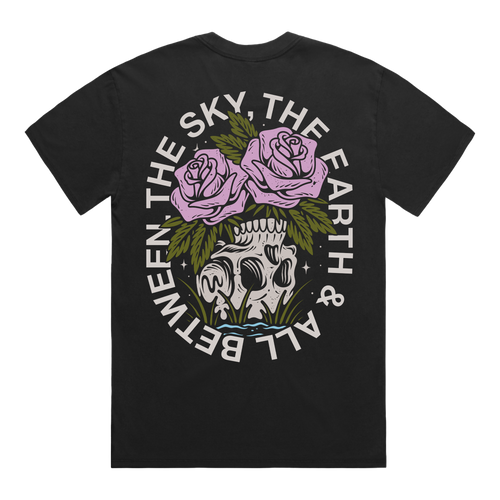 Back of a black short-sleeve t-shirt featuring a flower‚Äìskull graphic, with white text around it that reads ‚ÄúThe Sky, The Earth & All Between.‚Äù